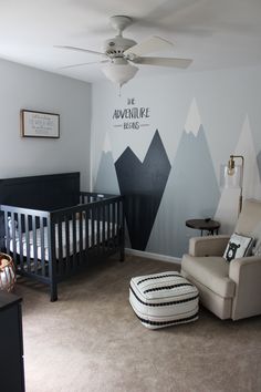 a baby's room with mountains painted on the wall and a crib in the foreground