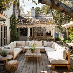 an outdoor living area with couches, tables and lights hanging from the ceiling above