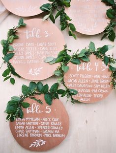 wedding seating signs with greenery on them are hanging from the side of a wall