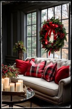 a living room decorated for christmas with red and white pillows, wreaths and candles