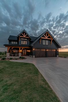 a large house sitting on top of a lush green field under a cloudy sky at dusk