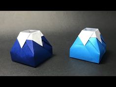 two blue origami boxes sitting on top of a black table next to each other