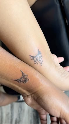 two people holding hands with tattoos on their arms and legs, both showing the same tattoo