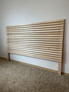 a wooden slatted headboard against a wall in a room with carpeting