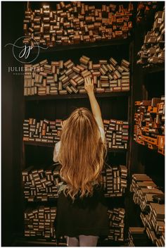 a woman is reaching up to look at stacks of books