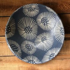 a black and white plate sitting on top of a wooden table next to a wall