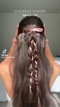 a woman with long brown hair and pink ribbon in her hair is shown from the back