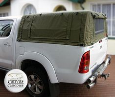 the back end of a white truck with a tarp on it's bed