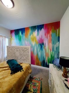 a bed room with a neatly made bed and a large colorful painting on the wall