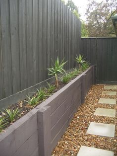 an outdoor garden with gravel, rocks and succulents on the side of a fence