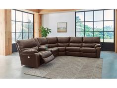 a large sectional couch with recliners in front of two windows and a rug on the floor