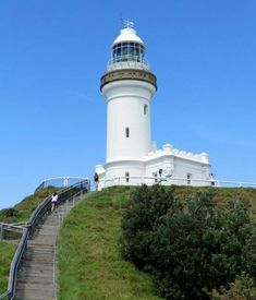 a lighthouse on top of a hill with stairs leading up to it and people walking around