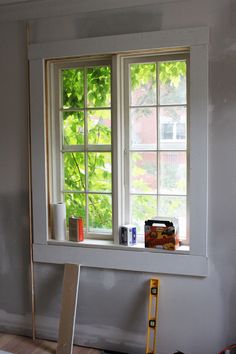 the window is being painted and ready to be installed in the room with the ladder