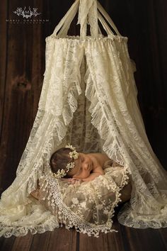 a baby is sleeping in a white crib with lace on the top and bottom