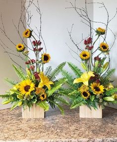 three vases with sunflowers, ferns and other flowers on a counter top