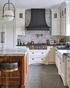 a kitchen with marble counter tops and white cabinets, along with an island in the middle