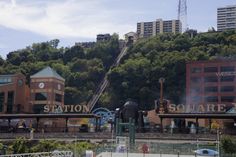 a train station with stairs leading up to the top and buildings on the other side