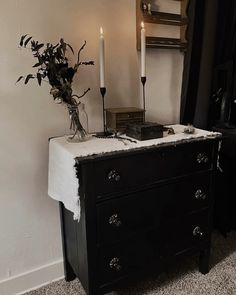 a black dresser with two candles on it