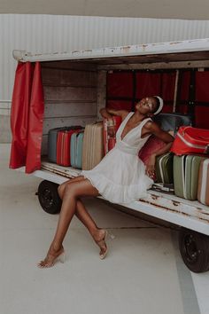 a woman sitting in the back of a truck filled with luggage