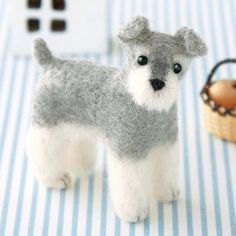 there is a small gray and white dog next to a basket on a blue striped table cloth