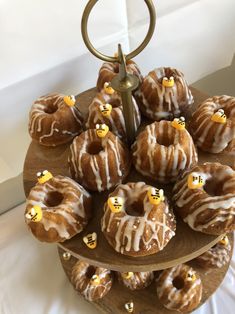 a wooden tray topped with donuts covered in frosting and mini honeybees