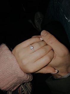 a woman holding the hand of a man who is wearing a diamond engagement ring on his finger