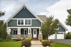 a blue house with white trim and two car garages on the front door is shown