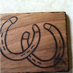 a wooden sign with the letter c on it's side and an outline of a horseshoe