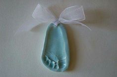 a blue baby foot ornament with a white ribbon hanging from it's side