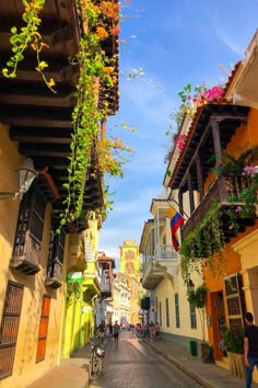 a narrow street lined with colorful buildings and hanging flower baskets on the side of it