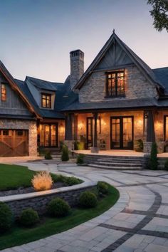 Luxury stone house with warm exterior lights and a well-manicured yard at dusk. Contemporary Country Home Exterior, Rustic Bungalow Exterior, Modern Farmhouse Aesthetic Exterior, House Cozy Exterior, Homes In The Country, Modern Rustic Mountain Home Exterior, Luxury Mountain Homes Exterior, Farm House Ideas Architecture, Cozy Cottage Interiors English Country