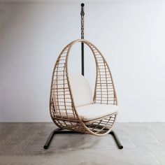 a hanging chair with a white cushion and black metal frame is shown in an empty room