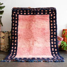 a pink and blue rug sitting on top of a wooden floor next to potted plants