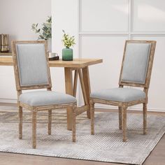 two chairs sitting next to each other in front of a table with a vase on it