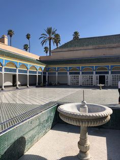 a fountain in the middle of a courtyard with blue and yellow tiles on it's walls