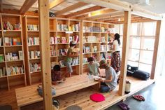 children are sitting on the bookshelves in a room with wooden floors and shelves full of books