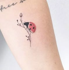 a ladybug tattoo on the left arm with words written below it and a flower