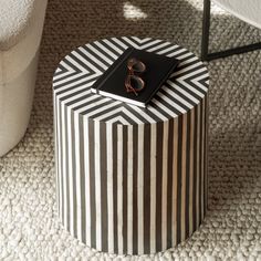 a black and white striped table with a book on it's top next to a chair