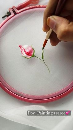 a person is painting a flower on a hoop