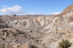 there are many mountains in the desert with sparse grass and bushes growing on each side