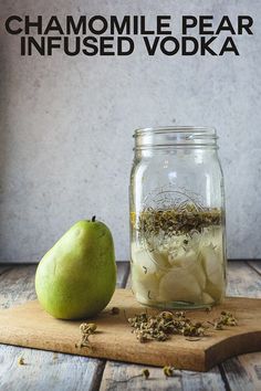 a glass jar filled with liquid next to an apple on top of a wooden cutting board