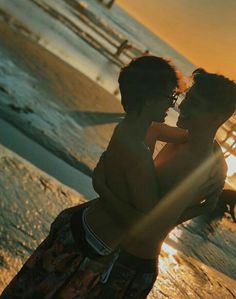 a man holding a child on the beach at sunset