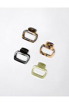 three different colored metal buckles on a white surface, one is black, the other is green