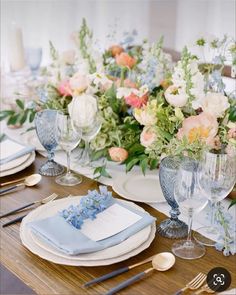 the table is set with blue and white dishes, silverware, and floral centerpieces