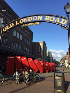 an old london road shopping area with bicycles parked under the sign and red bins