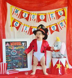 a baby dressed up as a pirate standing in front of a circus tent with an elephant