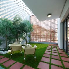 an outdoor dining area with grass and stone flooring, two chairs are facing the glass wall