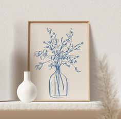 a vase with some flowers in it sitting on a shelf next to a framed photograph