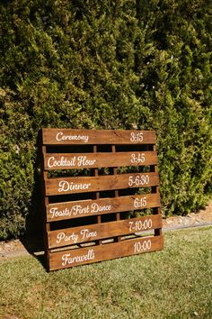 a wooden sign sitting on top of a lush green field