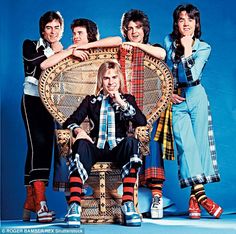 an old photo of four people sitting on a wicker chair and posing for the camera